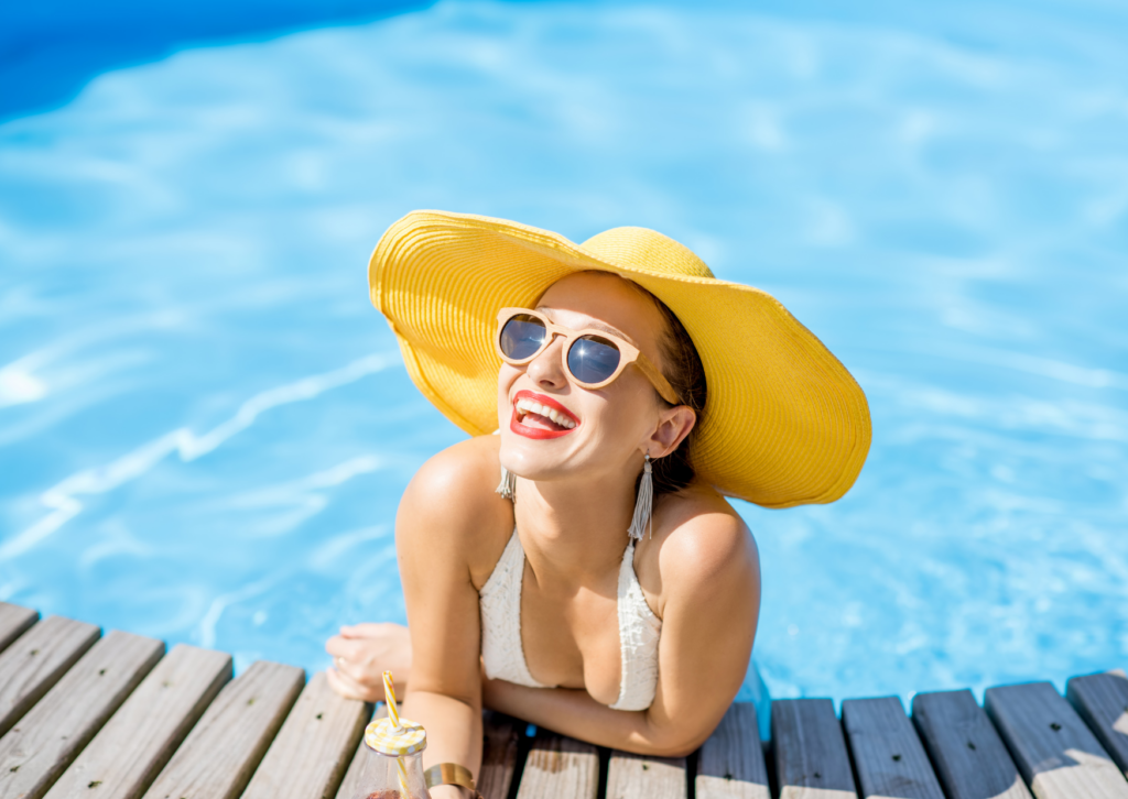 Smiling woman in hat by the pool.